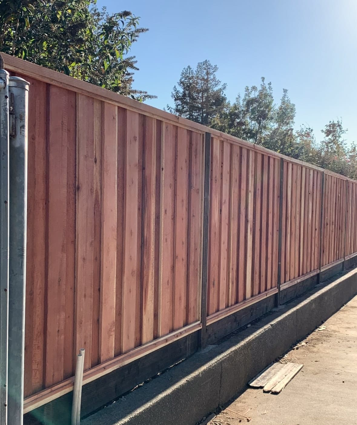 Tall redwood privacy fence with metal posts.
